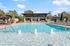 Elegant swimming pool area with crystal clear water and inviting sun loungers, set against a modern building and vibrant greenery.