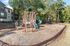 Inviting playground nestled in a serene apartment community, featuring a vibrant play structure surrounded by lush trees and well-maintained grounds.