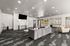 Elegant communal living area with a modern gray sofa, stylish accent chairs, and a large flat-screen TV, accented by contemporary decor and ample lighting.