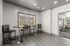 Elegant modern seating area with high stools and tables, featuring large windows and sleek gray tile flooring, perfect for casual gatherings.