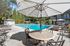 Inviting pool area with modern sun loungers, shaded seating, and lush greenery, perfect for relaxation and leisure.