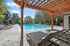 Inviting outdoor pool area with stylish lounge chairs and a wooden pergola, perfect for relaxation in a sunny, tranquil setting.
