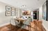 Elegant open-concept dining and kitchen area with stylish butterfly art and modern lighting, featuring a cozy dining table and sleek wooden flooring.