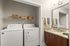 Chic laundry and bathroom area featuring modern washer and dryer, sleek granite countertop, and stylish wicker storage baskets.
