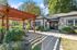 Charming apartment entrance with lush landscaping and a wooden pergola, offering a welcoming and serene atmosphere.