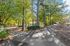 Serene pathway through lush green trees leading to a charming pavilion, perfect for relaxation and nature walks.