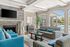 Elegant living room with striped sofas, cozy fireplace, modern decor, and large windows overlooking a poolside view.