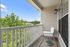 Charming balcony with a cozy chair, lush greenery, and clear blue skies for a perfect relaxing retreat.