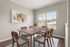 Bright and inviting dining area with modern wooden table and chairs, complemented by abstract wall art and natural light streaming through large windows.