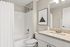 Modern bathroom design with elegant granite countertop, sleek fixtures, and stylish wall art above a pristine shower and bathtub.