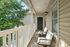Inviting apartment balcony with cozy seating area, surrounded by lush greenery and natural light.