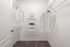 Spacious walk-in closet with neatly organized shelves and hanging space, featuring clean white shirts and stylish storage boxes.