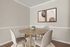 Modern dining area with a round wooden table, elegant beige chairs, and minimalist wall art in a bright, welcoming space.