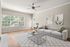 Bright and airy living room with large windows, elegant artwork, and a cozy sofa, perfect for relaxation.