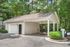 Charming detached garage with a covered carport surrounded by lush greenery, ideal for modern living.