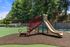 Charming playground with slide and shaded picnic area surrounded by lush greenery in a welcoming community park.