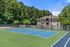 Inviting apartment complex with a private tennis court, surrounded by lush greenery and blue skies.