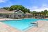 Charming outdoor pool area with crystal-clear water, surrounded by lush greenery and a stylish clubhouse.