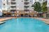 Inviting apartment complex boasting a sparkling outdoor pool with comfortable lounge chairs, surrounded by lush greenery and modern architecture.