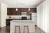 Elegant kitchen with dark wood cabinets, granite countertops, and stainless steel appliances, featuring a stylish island with modern bar stools.