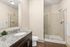 Elegant bathroom with a granite countertop, sleek sink, and a modern glass shower featuring beautiful tile work.