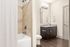Modern bathroom with elegant dark vanity, granite countertop, and sleek tile shower.