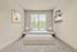 Cozy bedroom with natural light, featuring a plush bed, modern nightstands with elegant lamps, and stylish wall-mounted shelves.