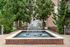 Tranquil courtyard fountain surrounded by lush greenery and elegant brick architecture, offering a serene outdoor retreat.