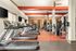 Modern fitness center with state-of-the-art treadmills, strength machines, and vibrant red flooring accentuated by sleek design elements.