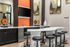 Modern communal space featuring a sleek bar with contemporary stools, a built-in TV, and stylish decor pieces on display.