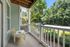 Charming apartment balcony with cozy seating, surrounded by lush greenery and offering serene views of a peaceful street.