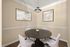 Charming dining nook with a round table, four plush chairs, and minimalist wall art, perfect for intimate gatherings.