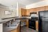 Modern kitchen with sleek black appliances, warm wooden cabinetry, and elegant countertops, perfect for culinary creativity.