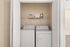 Modern laundry closet with sleek washer and dryer, complemented by stylish shelving for seamless organization.