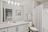 Elegant bathroom with marble countertop, modern fixtures, and a spacious mirror, reflecting a cozy bedroom.