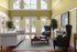Elegant living room with high ceilings, large windows, and luxurious furnishings, offering a poolside view through French doors.