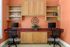 Chic home office setup with dual workstations, vibrant orange walls, and stylish wood cabinets for a modern productive space.