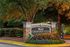 Inviting entrance to Creekside Vista Apartments, surrounded by lush greenery and vibrant flowers, offering a serene living environment.