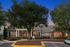 Charming apartment clubhouse with elegant stone facade, framed by lush greenery and illuminated by a vibrant sunset sky.