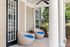 Charming apartment porch with cozy round wicker chairs featuring vibrant blue cushions, elegant white columns, and a ceiling fan for a relaxing outdoor ambiance.