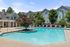 Inviting outdoor pool area with modern lounge chairs and lush greenery, set against elegant apartment architecture.