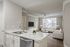 Elegant open-concept apartment featuring a sleek marble countertop in the kitchen, modern living room with ample natural light, and contemporary furnishings.
