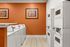Bright, modern laundry room with vibrant orange walls, sleek washing machines, and contemporary artwork.