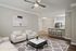 Modern open-concept living area featuring a cozy seating arrangement, stylish marble coffee table, and a chic kitchen with sleek barstools.