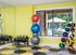 Vibrant fitness room with colorful exercise balls, kettlebells, and a scenic pool view.