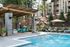Luxurious poolside oasis with comfortable lounge chairs, shaded seating area, and lush greenery, perfect for relaxation and entertainment.