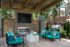 Inviting outdoor lounge featuring modern teal seating, a sleek fireplace, and a grill, perfect for entertaining in a lush, tranquil setting.