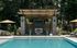 Luxurious outdoor pool area featuring a stylish cabana with comfortable seating, surrounded by lush greenery and umbrellas, perfect for relaxation and entertainment.
