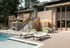 Luxurious outdoor pool area with stylish loungers, elegant seating, and a modern wood-paneled exterior.