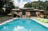 Luxurious apartment complex showcasing a stunning pool with modern loungers, surrounded by lush greenery and elegant architecture.